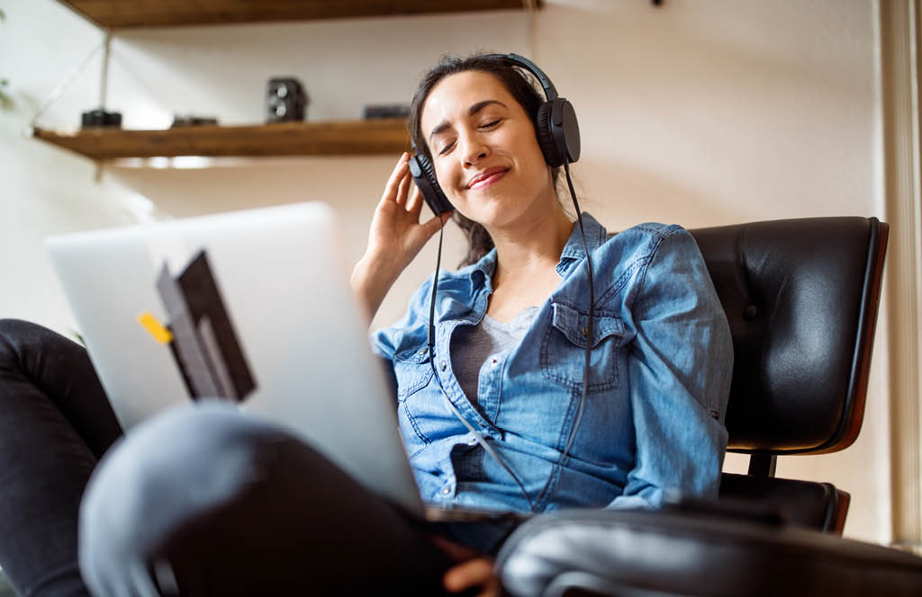 Mulher escutando musica enquanto mexe no notebook.