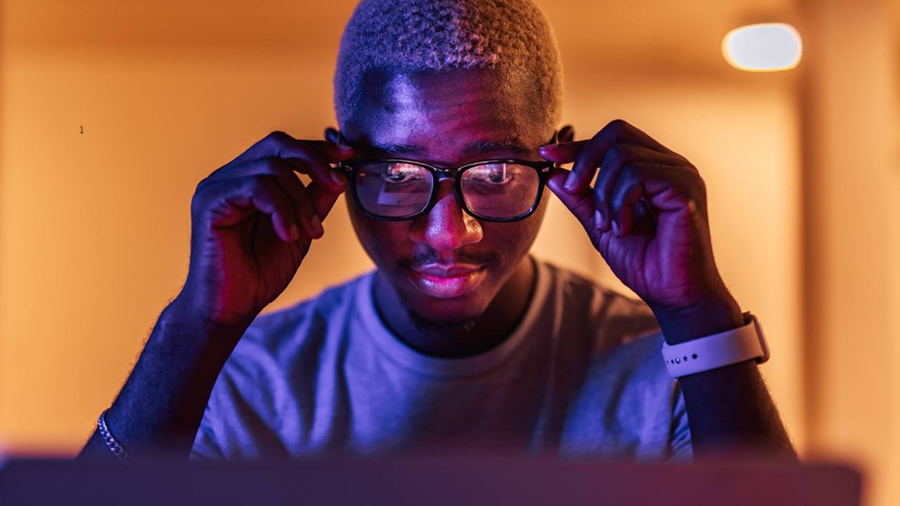 Fotografia de um homem negro trabalhando com um laptop na sala.