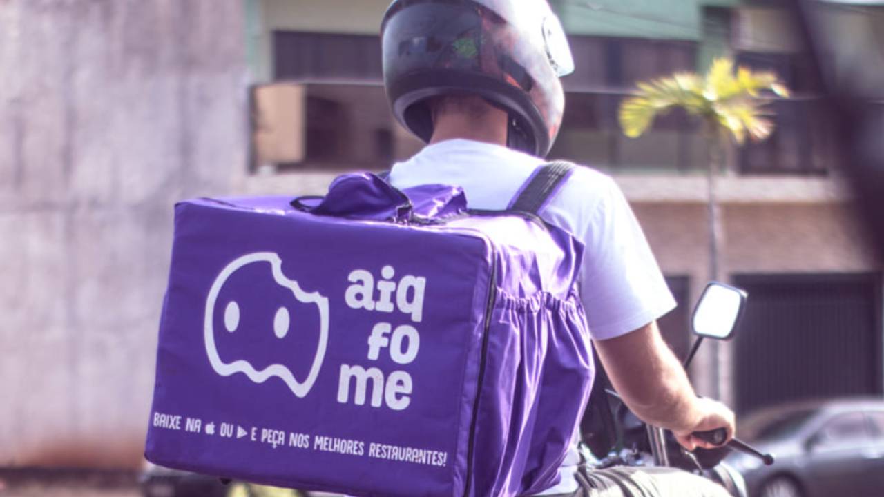 Fotografia de um motoboy com a bolsa da Ai Que fome.