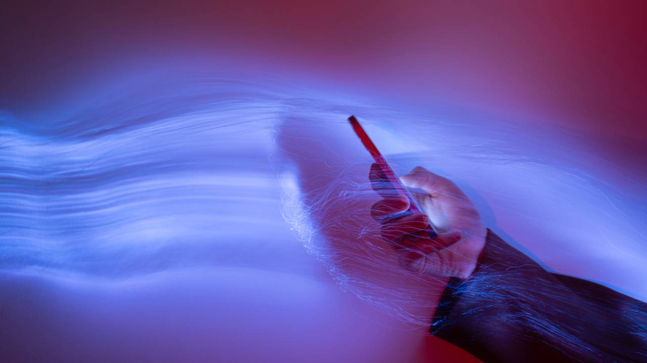 Close-up de uso de telefone celular em fundo holográfico.