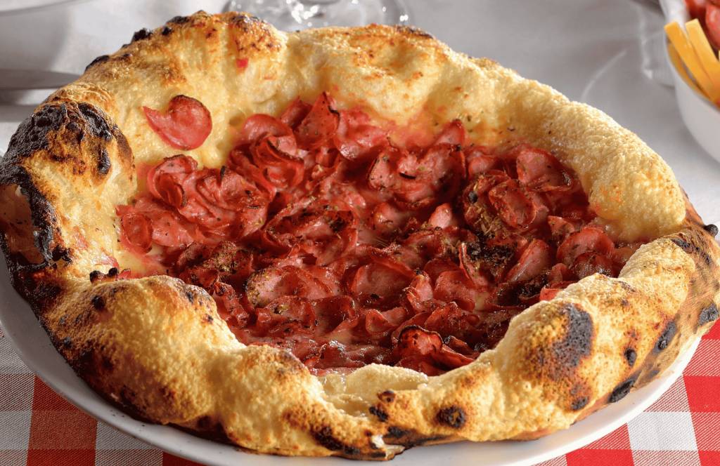 Uma pizza de calabresa sobre um prato branco.